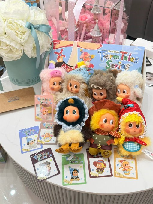 A display of 'Farm Tales Series' Pop Mart collectible plush toys featuring various character dolls in costumes arranged with their character cards.