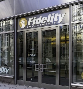 The image shows the glass entrance of a Fidelity Investments branch, featuring its logo and name displayed above the doors. The image visually reinforces the post by depicting Fidelity's corporate presence, aligning with the claim that the investment giant made a significant $21 million Bitcoin purchase amid whale accumulation.