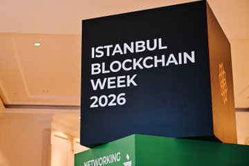 The image features a large black cube sign that reads " Istanbul Blockchain Week 2026" against a white background, with the words "Istanbul" written above it. The sign is placed on top of two green boxes, creating an interesting visual contrast between the dark and light colors. The text on the sign indicates that this event is focused on building foundational financial infrastructure for the AI agent era, which could be related to blockchain technology or other aspects of the digital world.