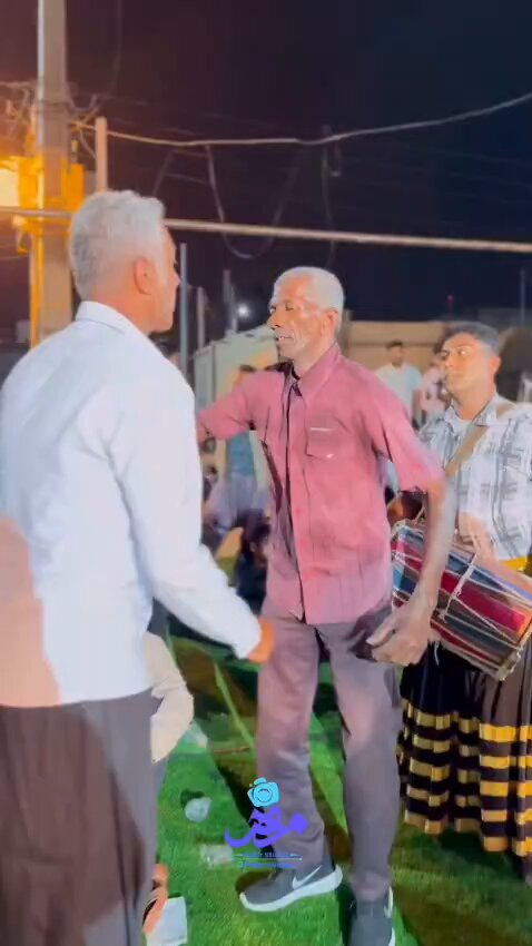 The image shows a group of people standing together, with two men shaking hands over some grass. One man has grey hair and is wearing a pink shirt while another man has white hair and is wearing a red shirt. The background includes a street scene with power lines running across it. A caption in the image reads "Crypto investors trying to stay calm during the dumps #btc #eth #sol".