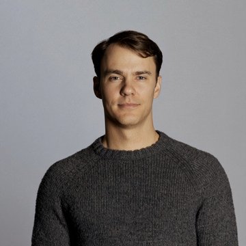 A man in a dark gray sweater poses for a portrait against a neutral gray background. The image accompanies a report about Coinbase co-founder Fred Ehrsam pursuing Venezuelan oil field investments amid Washington's reshaping of the country's energy sector.