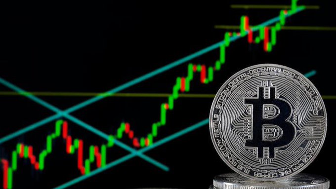 In this image, there is a coin with Bitcoin symbol on top of another coin placed near a computer screen displaying cryptocurrency price movement against a night skyline background showing stock markets. The Bitcoin price has been rising above $65,000 for several weeks after an announcement of peace between two countries, which is now reflected in the current price shown by the monitor. This demonstrates how the post relates to the content on the image through the concept of tracking and analyzing cryptocurrency prices and market trends.