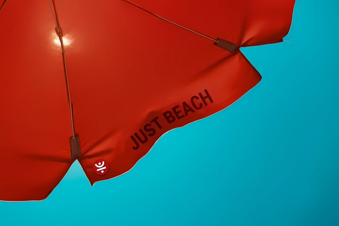 A red beach umbrella emblazoned with the text "JUST BEACH" and a small umbrella logo stands against a turquoise sky, visually evoking the "sizzling summer" metaphor used in the post. The umbrella's shade symbolizes protection and foundation, paralleling the description of TRX as the "foundational fuel" driving TRON's DeFi Summer ecosystem.