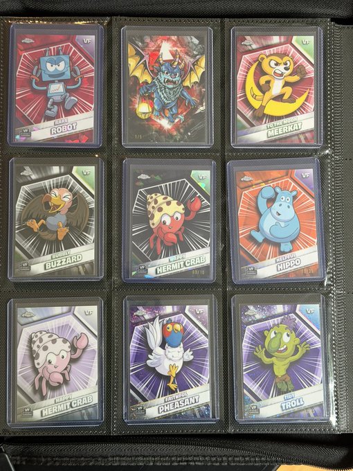 A photograph displays a collector's binder page containing nine trading cards featuring cartoonish sea creatures, labeled with names such as "ROBOT", "MEERKAY", "BUZZARD", and "HERMIT CRAB".