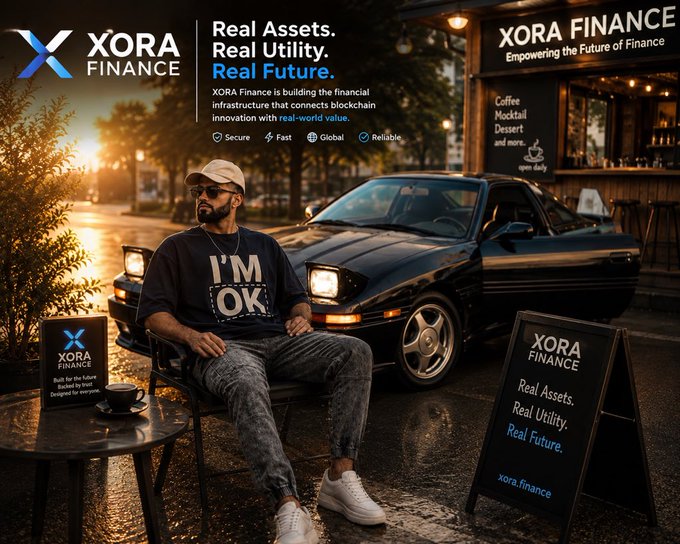 A promotional advertisement for 'XORA FINANCE' featuring the tagline 'Real Assets. Real Utility. Real Future.' with a man sitting on a chair wearing an 'I'M OK' shirt, positioned next to a black sports car outside a coffee shop.