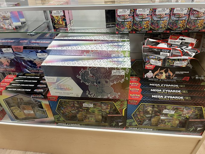 This image shows a display of Pokémon trading cards, including several "Mega Zygarde GX Premium Collection" boxes and a "Prismatic Evolution Super Premium Collection" box priced at $349.99, which aligns with the accompanying post's mention of the SPC.