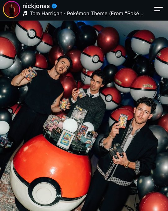 An Instagram post by nickjonas showing the Jonas Brothers posing with Pokémon trading cards surrounded by Pokéball-themed balloons, with Tom Harrigan's Pokémon Theme playing.