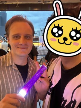 Two people pose together at an indoor event, with one holding a purple glowing light stick while the other is playfully obscured by a cartoon bunny sticker, capturing the social atmosphere of the Arcium Seoul meetup.