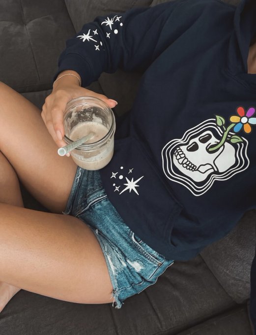 A person wearing a navy blue hoodie with a skull and flower graphic relaxes on a couch while holding a glass mug with a straw containing a creamy beverage, capturing a cozy midweek moment.

The image reflects the casual, laid-back vibe of a busy Wednesday, showing someone taking a break from a packed schedule of meetings and projects to enjoy a drink.
