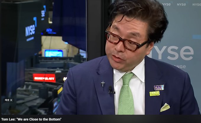 A man wearing glasses, a navy suit, and a green tie speaks during a CNBC interview on the NYSE trading floor, with a chyron reading "Tom Lee: 'We Are Close to the Bottom.'" The image accompanies an article in which Tom Lee shares his outlook that the market is near its bottom, discussing expected shifts in semiconductors, interest rates, Ethereum, and gold.