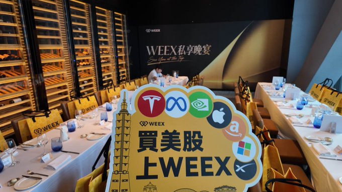 An event setup with rows of dining tables and wine racks, featuring a sign with logos for Tesla, Meta, NVIDIA, Apple, Amazon, Microsoft, and XRP, reading 'WEEX 私享晚宴' and '買美股上WEEX'.