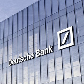 The image shows a modern glass building facade featuring the "Deutsche Bank" name and its distinctive slash logo prominently displayed. This visually ties into the announcement that Deutsche Bank, Germany's largest bank, is launching $1.7 trillion worth of Bitcoin custody services for clients.