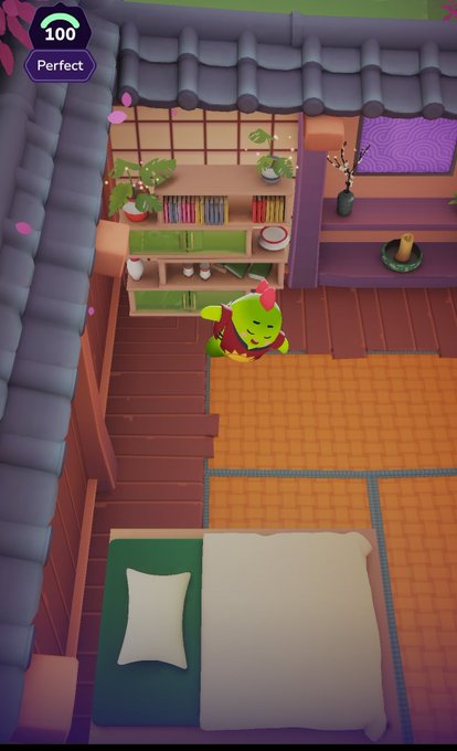 Top-down view of a cozy Japanese-style room in a mobile game, featuring a green goblin-like character with red hair, a kitchen area, and a bed, with a '100 Perfect' score indicator.