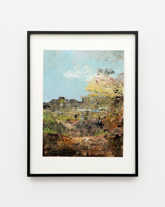 A framed mixed-media artwork displayed on a light wall, showing an abstract landscape with a blue sky and textured earth tones in greens, browns, and yellows.