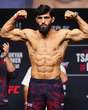 A muscular male UFC fighter flexes both biceps on stage during what appears to be an official weigh-in, with visible text including "TSAR" and "UFC" in the background. The image likely relates to the post's discussion about Arman, a fighter known for his chiseled physique, with fans debating his chances in an upcoming bout.