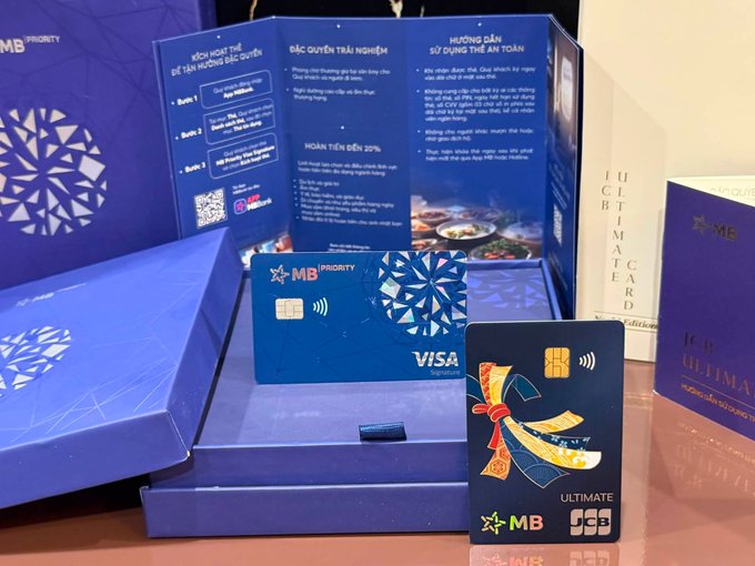 The image showcases an MB Priority Visa card and an MB JCB Ultimate card displayed in their elegant blue presentation boxes, alongside informational brochures about the bank's privileges and safety guidelines in Vietnamese. This visual aligns with the post's theme of curating a purposeful wallet, highlighting the premium MB Signature and MB JCB Ultimate cards chosen for their travel, lifestyle, and insurance benefits.
