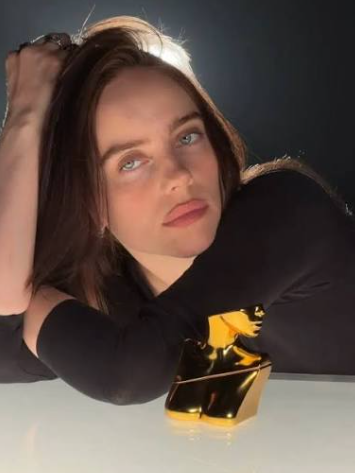 A young woman with long dark hair and blue eyes poses with her arm resting behind her head next to a golden crypto-paper-airplane-shaped trophy, the image used as a visual flex for the post's bullish crypto commentary praising the ticker calls ($BTC, $HYPE, $LIGHTER, $PONS, $TROLL) as "appetizers" in a freshly restarted bull cycle.