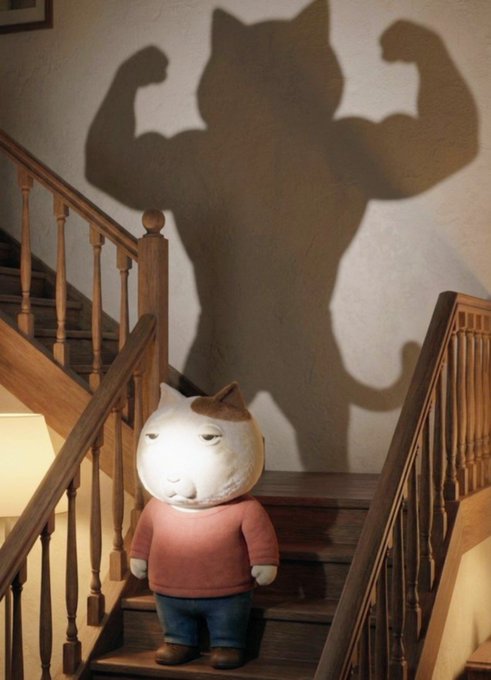 A cartoon cat character in a pink sweater stands on a wooden staircase, casting a dramatic muscle-bound "hero" shadow on the wall behind it—visually playing on the post's joke about $ket "working" for the user while they sleep, even though the shadow reveals a far more powerful version of the character.