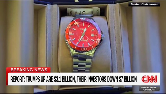 A red "$TRUMP" wristwatch, photographed by Morten Christensen during Trump's memecoin dinner, appears on a CNN "Breaking News" segment with the chyron reading "REPORT: TRUMP'S UP ARE $3.1 BILLION, THEIR INVESTORS DOWN $7 BILLION," credited to CNN's Erin Burnett Outfront.