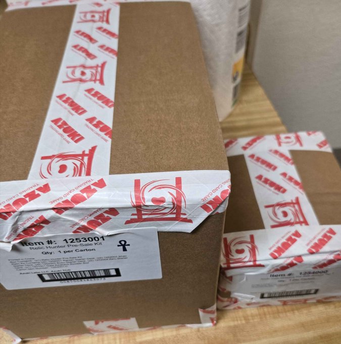 Two cardboard boxes sealed with custom 'AZMT' (Azure Mint) branded tape, labeled as Relic Monster Pre-Sale Kits.