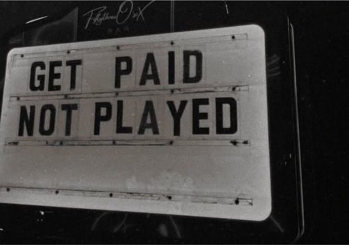 The image shows a sign reading "GET PAID NOT PLAYED" alongside a tagline referencing "Fight With X RAM." It ties into the caption's theme of users being compensated by X (the platform), humorously emphasizing the contrast between those who actually got paid versus those who felt left out of MoonPay's payouts.