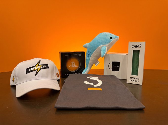 A collection of branded merchandise including a "#RECKLESS" cap, a folded gray t-shirt, a blue dolphin plush, an "AERONAUTS EYEGLASSES" box, a "JANO OMEGA CANDLE," and a small mug are arranged against a vibrant orange background, embodying the "orange pill" aesthetic promoted by @cypherpunkstore.