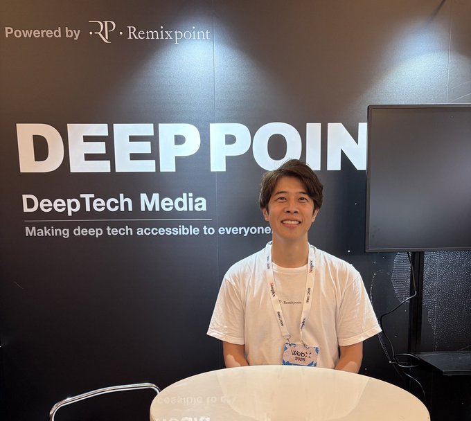A smiling man wearing a "WebX 2025" lanyard sits at a table in front of a "DEEPPOINT DeepTech Media - Making deep tech accessible to everyone" backdrop (powered by Remixpoint), appearing ready for an interview or presentation at the WebX event, with the Jasmy community wishing him success.