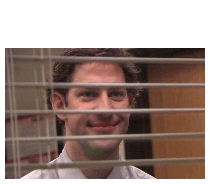 A photograph of Jim from The Office (John Krasinski) smiling, viewed through horizontal window blinds.