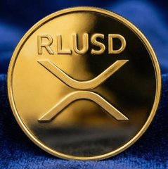 A close-up of a gold Ripple (XRP) coin featuring the prominent inscription "RLUSD" set against a blue fabric background. The image visually emphasizes the rapid growth of Ripple's RLUSD stablecoin highlighted in the post, symbolizing its emergence as the third-fastest-growing stablecoin of 2026.