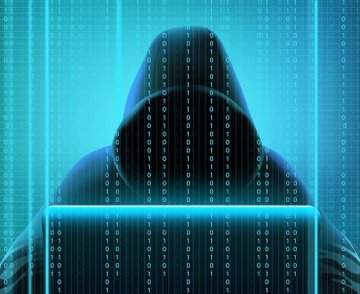 A hooded figure sits behind a laptop, partially obscured by cascading columns of binary code, symbolizing the hidden and anonymous nature of cyber threats. The image reinforces the post's warning about the security risks and delayed withdrawals on the AscendEX cryptocurrency exchange.