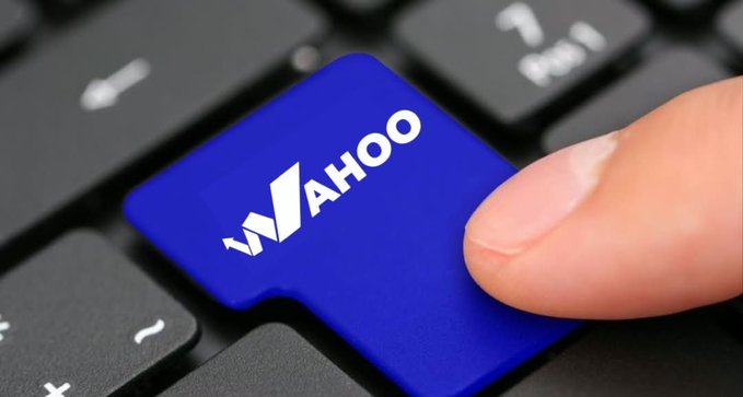A close-up of a finger pressing a blue key on a black keyboard that has the 'YAHOO' logo printed on it.