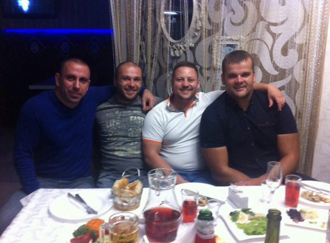 Four men sit together at a dinner table, smiling for the camera while enjoying a meal with drinks and various dishes spread out before them. The image relates to the post by illustrating the carefree moment in 2013 when the author was out socializing with friends, oblivious to the Bitcoin opportunity he was missing.