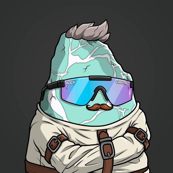An illustration of a character resembling a cracked teal stone or rock with a gray tuft of hair, wearing blue and purple ski goggles labeled 'ROCK CAPITAL' and a brown mustache, dressed in a white straitjacket.