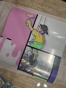 A silver holographic mylar trading card storage bag featuring a cartoon character in a yellow shirt and cap, with pink liquid drip graphics.