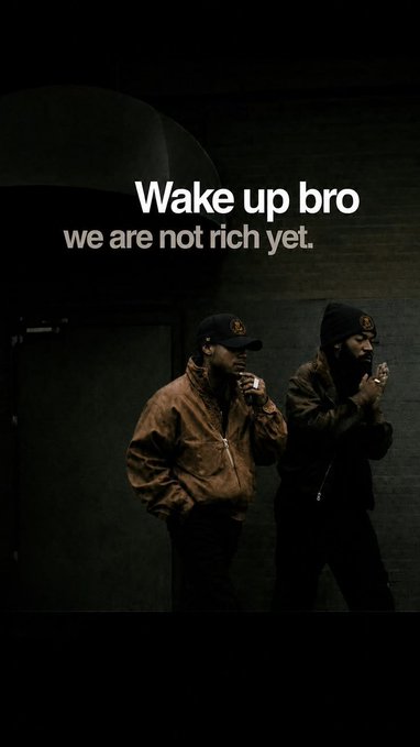 The image shows two men in dark jackets and caps against a dimly lit background, with overlay text reading "Wake up bro / we are not rich yet." The motivational caption "Good morning CT, Manifesting a win today" pairs with the image's hustle-focused message, reinforcing a mindset of working toward financial success.