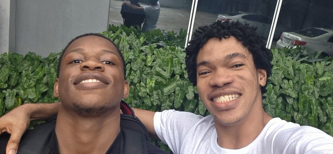 Two friends smile for a selfie in front of greenery, likely outside a building, capturing a casual "good morning" moment between them that matches the post's friendly greeting tagged to @Romeo_Onchain.