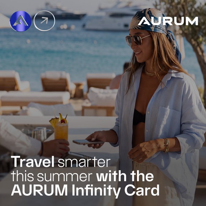 The image shows a woman at a beach club making a contactless payment by tapping her smartphone at a table where tropical cocktails are served, with luxury yachts visible in the background. Text overlay reads "AURUM" alongside the caption "Travel smarter this summer with the AURUM Infinity Card."

The image visually reinforces the post's message by depicting a real-world scenario of a traveler effortlessly paying at a high-end seaside venue with her phone, illustrating the card's worldwide acceptance, contactless Apple Pay/Google Pay functionality, and seamless payment experience without traditional KYC requirements.