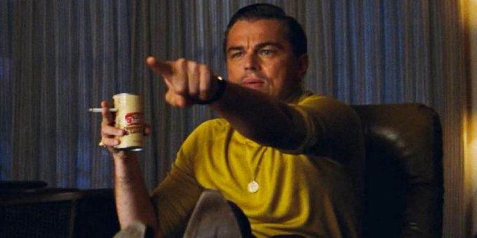 Leonardo DiCaprio points confidently while holding a cigarette and a coffee cup, channeling a "Wolf of Wall Street" energy that mirrors the bold optimism of a crypto and NFT bull run.