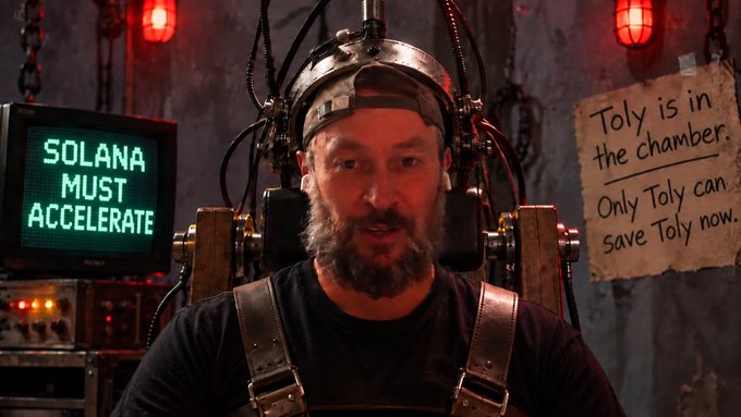A man with a beard strapped into a steampunk-style contraption. Beside him, a monitor displays 'SOLANA MUST ACCELERATE' and a handwritten sign reads 'Toly is in the chamber. Only Toly can save Toly now.'