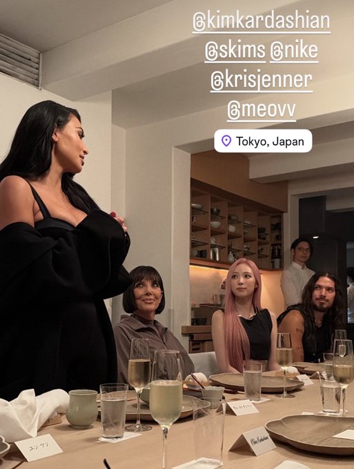Kim Kardashian stands in a black dress tagging @kimkardashian, @skims, @nike, @krisjenner, @meovv, with a location tag reading 'Tokyo, Japan', while Kris Jenner, a pink-haired woman, and others are seated at the table.
