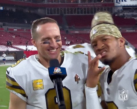 Two New Orleans Saints football players being interviewed after a game, with an NFL microphone visible and confetti in the background.