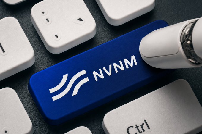 A close-up of a keyboard with a prominent blue key labeled 'NVNM' being pressed by a white stylus or finger.