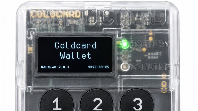 A transparent COLDCARD hardware wallet device displays "Coldcard Wallet" on its screen along with "Version 2.0.3" and the date "2023-04-25," with visible buttons labeled 1, 2, and 3 and a green LED indicator. The image illustrates the very type of secure Bitcoin storage device being targeted in the escalating phishing attack waves draining BTC from hundreds of addresses at unprecedented speeds.