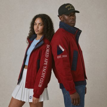 Two models showcase the burgundy Bored Ape Yacht Club jacket featuring "BORED APE YACHT CLUB" text down the sleeve and "EST. 2021" on the chest, paired with the matching black "BAYC" cap—promoting the limited edition BAYC Yacht Jacket and Sail Hat drop for Manifest 001: Flying Colors.