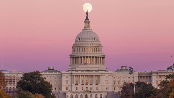 The image shows the U.S. Capitol Building at dusk with a full moon rising behind its iconic dome, set against a pink-hued sky. The scene visually reinforces the post's news about the Clarity Act, a piece of legislation being negotiated in Congress, connecting the legislative developments to the seat of American lawmaking.