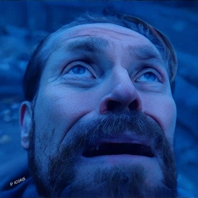 A close-up, blue-tinted portrait shows a bearded man looking upward in awe, marked with the text "D ICONS".