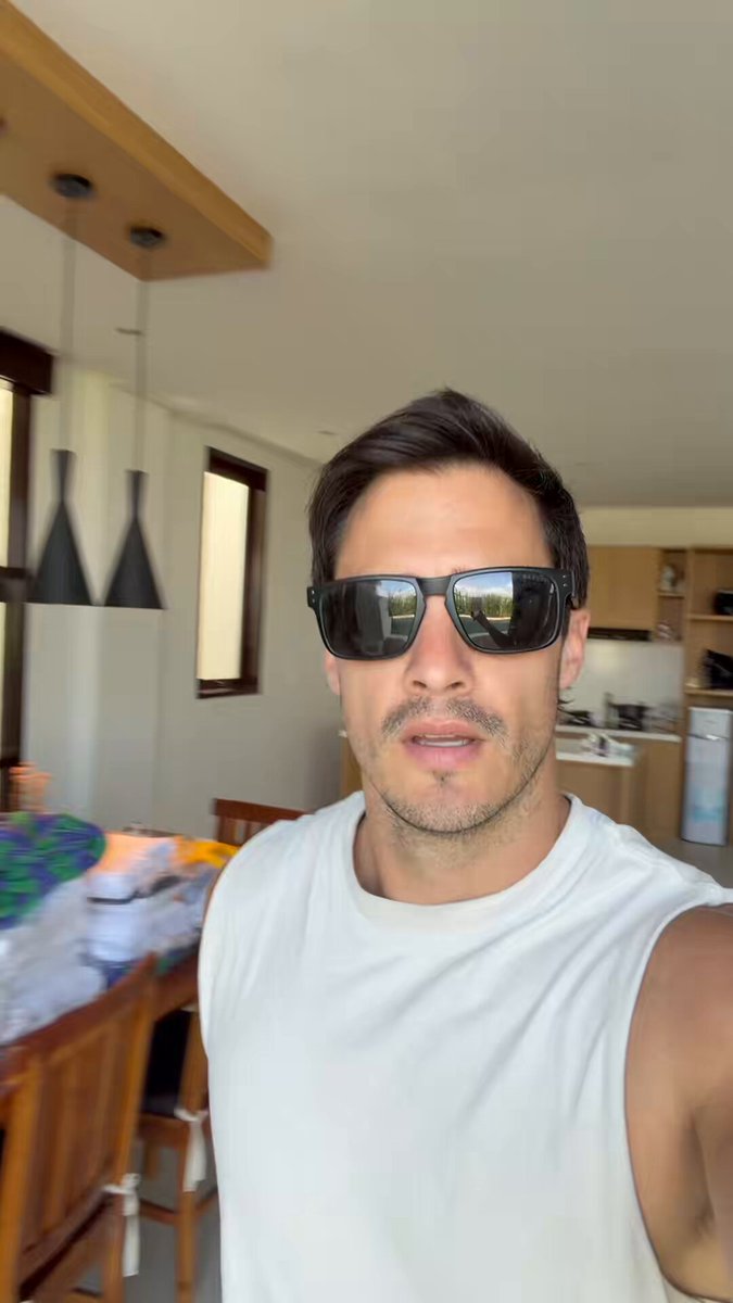 The image features a man wearing sunglasses, standing in front of a dining table that has various items on it such as bottles and bowls. The man appears to be posing for a photo or taking part in an online discussion about Pocket Dragons, a popular video game series.