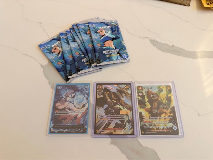 A fan-fanned stack of Azuki TCG "Participant" booster packs sits above three holographic cards featuring characters "Guo Jian," "Yumi," and "Chillax Bear" on a marble surface, showcasing collectible prizes from regional TCG events being shared on the Holo app.