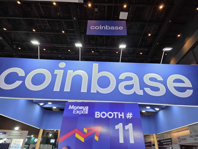The bright blue Coinbase Booth #11 sign towers over attendees at Money Expo 2026 in Mumbai. The bold "coinbase" branding overhead reinforces the company's presence at the Jio World Convention Centre event.