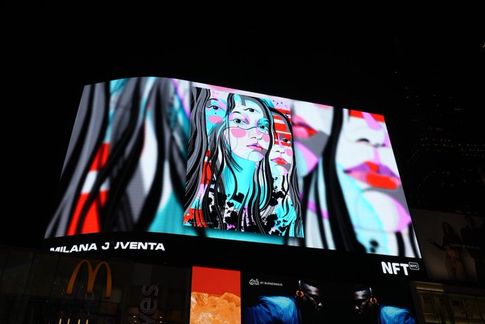A brightly lit outdoor billboard at night displays stylized pop-art portraits of three women in vibrant blue and red tones, with text reading 'MILANA J JVENTA' and 'NFT art' above a McDonald's logo.